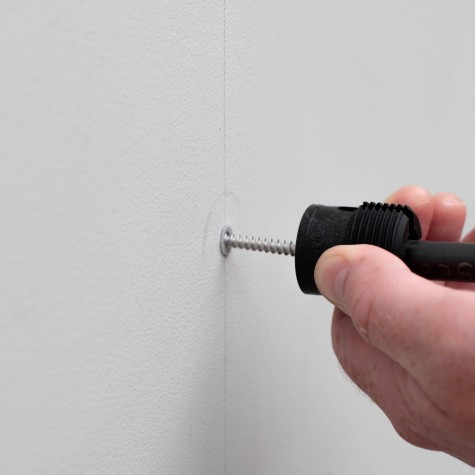 a screw going into a wall plug ready to support the green wall panel